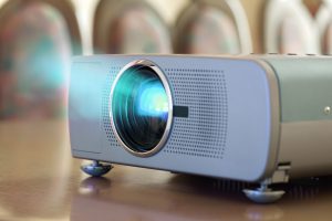 Projector on office table ready for presentation with chairs in background